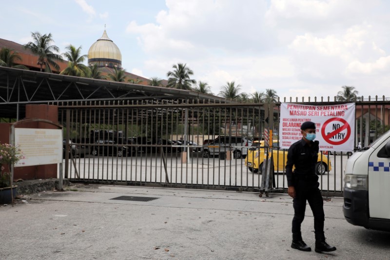 &copy; Reuters. FILE PHOTO: A police officer wearing protective mask stands guard outside the Seri Petaling Mosque in Kuala Lumpur