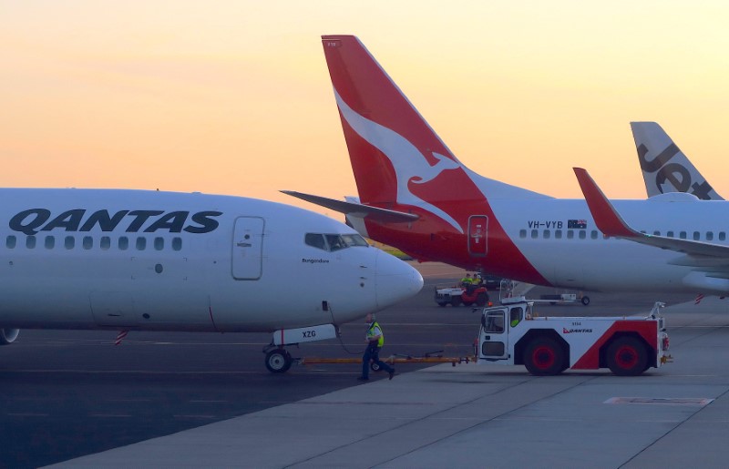 © Reuters. Los trabajadores son vistos cerca de Qantas Airways, la aerolínea nacional de Australia, el avión Boeing 737-800 en la pista del aeropuerto de Adelaida