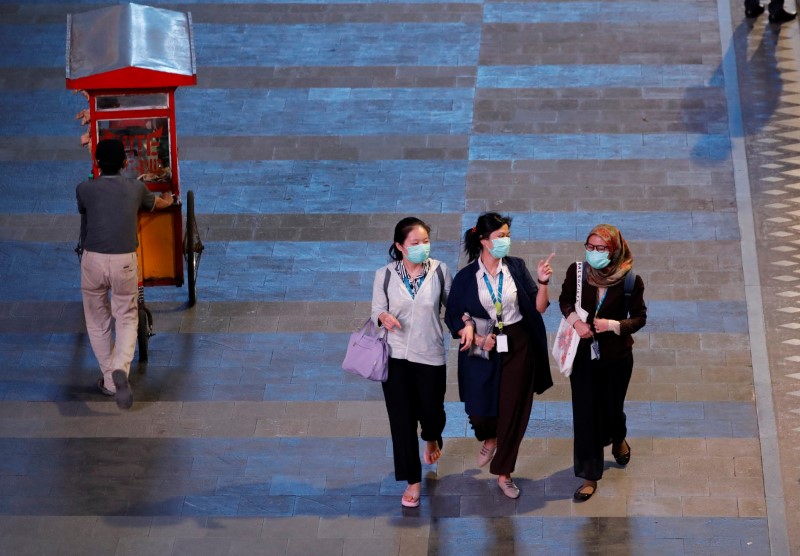 &copy; Reuters. Women wearing masks pass a vendor on a sidewalk of the main road after office hours, amid the spread of coronavirus disease (COVID-19) in Jakarta