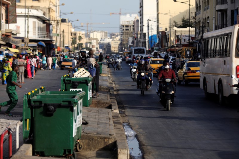 © Reuters. A man wears a face mask, due to the global coronavirus disease (COVID-19) outbreak, as he rides his motorbike along a busy shopping street in Dakar