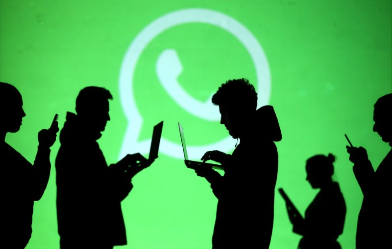 © Reuters. FILE PHOTO: Silhouettes of laptop and mobile device users are seen next to a screen projection of Whatsapp logo in this picture illustration