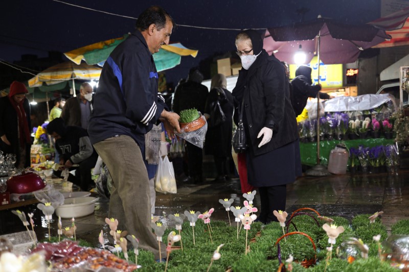 © Reuters. An Iranian woman wears a protective face mask, amid fear of coronavirus disease, as she buys flowers, ahead of the Iranian New Year Nowruz, March 20, in Tehran