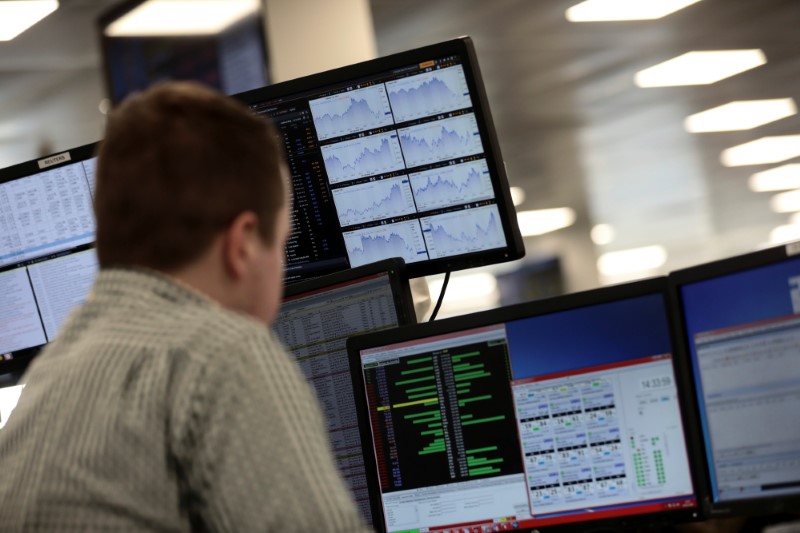 © Reuters. FILE PHOTO: Traders looks at financial information on computer screens on the IG Index trading floor