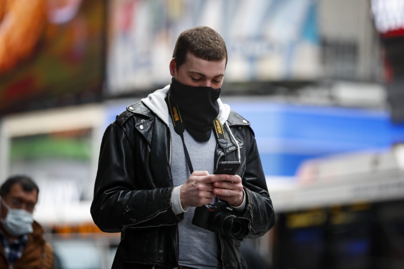 © Reuters. A man covers his face as he walks through a nearly empty Times Square, as people react to coronavirus disease (COVID-19) in New York