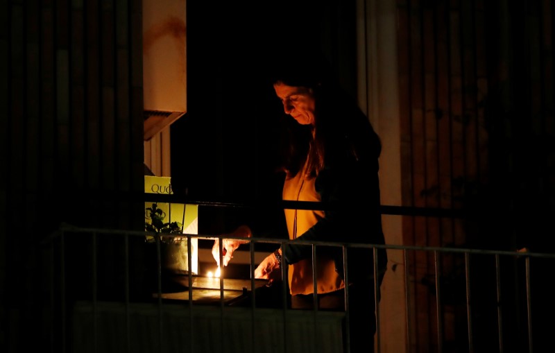 © Reuters. A woman lights a candle on her balcony as faithful across Italy say a prayer for people suffering from coronavirus disease (COVID-19)