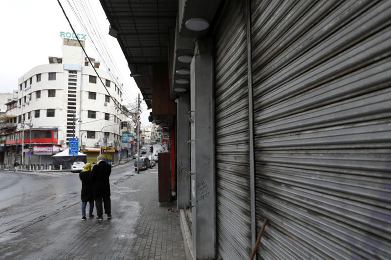 © Reuters. FILE PHOTO: People walk next to closed shops in Amman