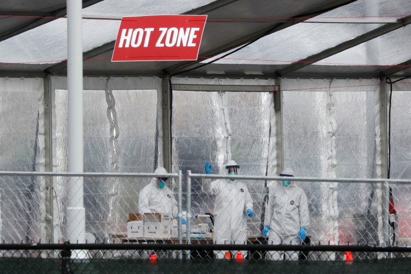 © Reuters. Health workers in personal protective equipment (PPE) work inside a new drive-thru coronavirus disease (COVID-19) testing center in the Staten Island New York