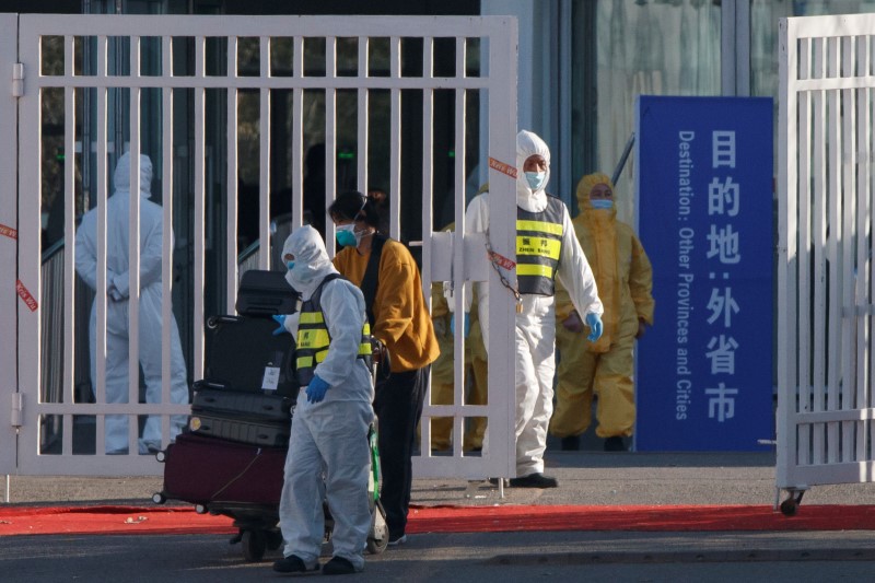 © Reuters. FILE PHOTO: March 17, 2020 picture of staff in protective suits accompanying a passenger outside a centralized facility for screening and registration near the Beijing Capital International Airport