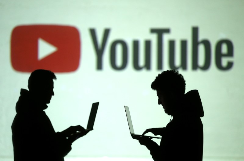 © Reuters. Silhouettes of mobile device users are seen next to a screen projection of Youtube logo in this picture illustration