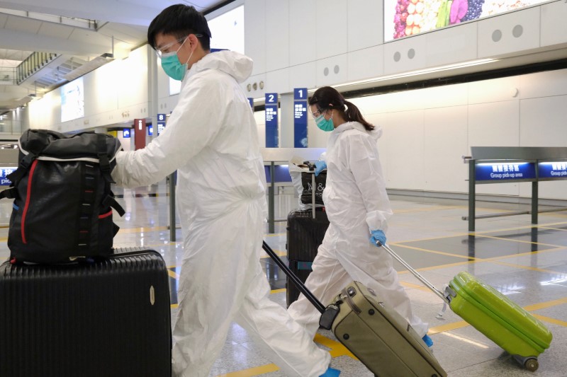 © Reuters. Passengers in protective suits arrive at Hong Kong International Airport, following the novel coronavirus disease (COVID-19) outbreak, Hong Kong