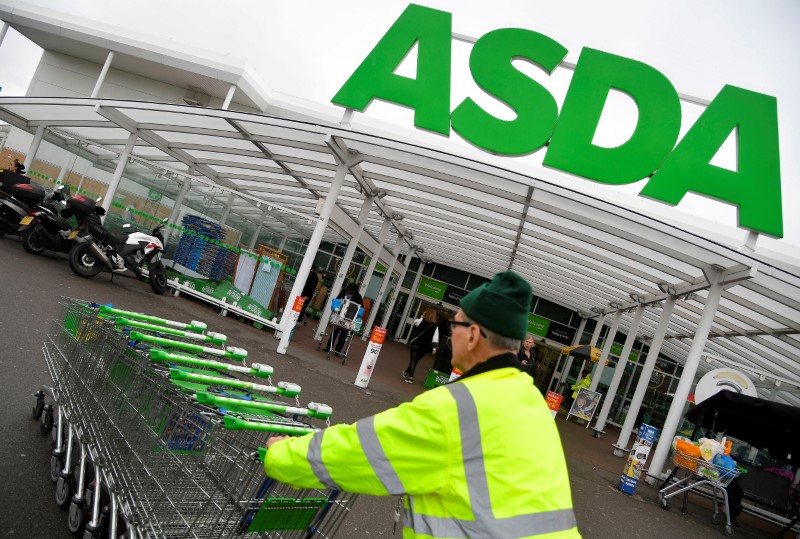© Reuters. FILE PHOTO: A worker pushes shopping trolleys at an Asda store in west London, Britain