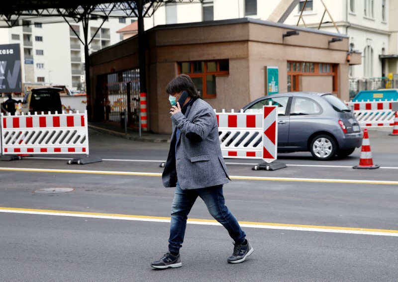 © Reuters. FILE PHOTO: A pedestrian wearing a mask walks through the Swiss-Italian border during the outbreak of the coronavirus disease (COVID-19), in Chiasso