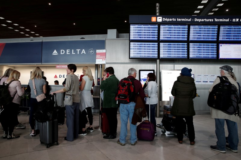 © Reuters. FILE PHOTO: People line up at the Delta Air Lines ticketing desk inside Terminal 2E at Paris Charles de Gaulle airport