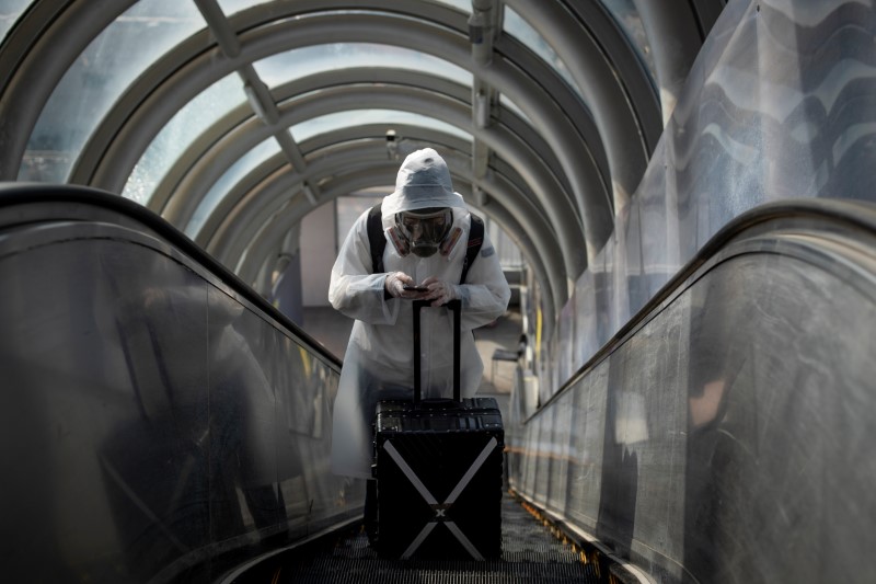 © Reuters. A traveller wearing protective clothing and a full-face mask goes up an escalator after leaving Beijing Railway Station as the country is hit by an outbreak of the novel coronavirus