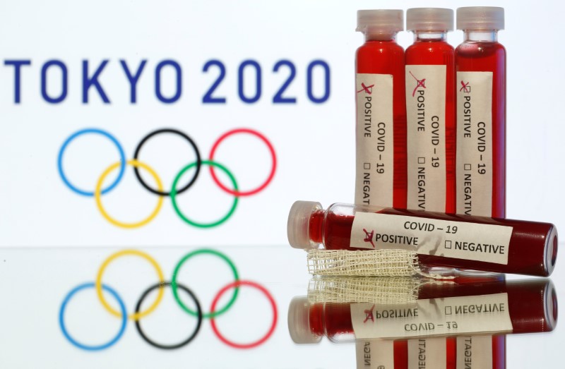 © Reuters. Fake blood in seen in test tubes labelled with coronavirus disease (COVID-19) in front of a displayed Tokyo 2020 Olympics logo