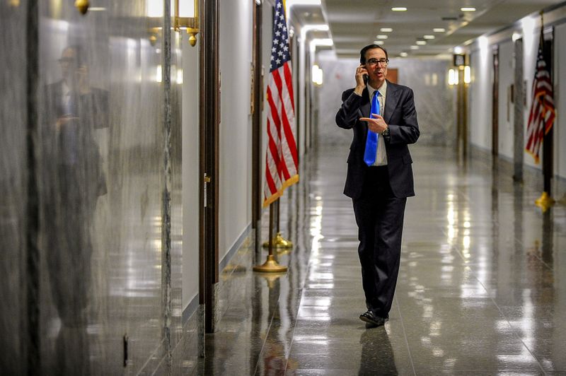 © Reuters. FOTO DE ARCHIVO: El secretario del Tesoro, Steve Mnuchin, atiende una llamada telefónica en el pasillo fuera de una reunión para concluir el trabajo sobre la legislación de ayuda económica del coronavirus.