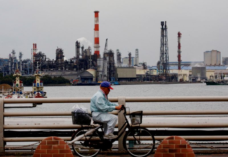 &copy; Reuters. A man cycles past chimneys of facotries at the Keihin Industrial Zone in Kawasaki