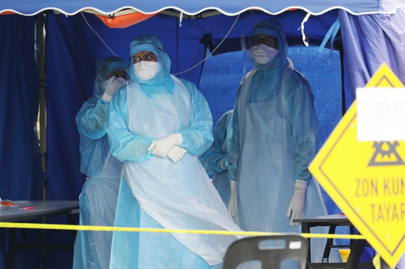 &copy; Reuters. Health workers in protective suits wait for patients in a tent erected to test for coronavirus at a clinic, in Kuala Lumpur