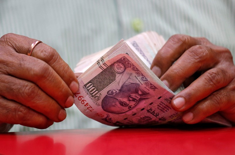 © Reuters. FILE PHOTO: A man counts Indian currency notes inside a shop in Mumbai