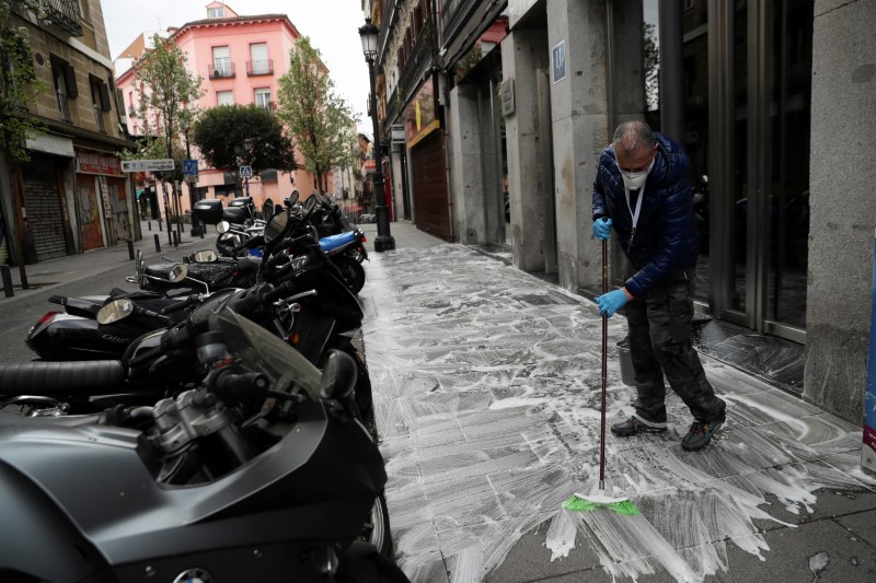 &copy; Reuters. FOTO DE ARCHIVO: Carlos, el dueño del Hotel Freedom, que cerró debido al brote de coronavirus, friega la acera frente al hotel en Madrid