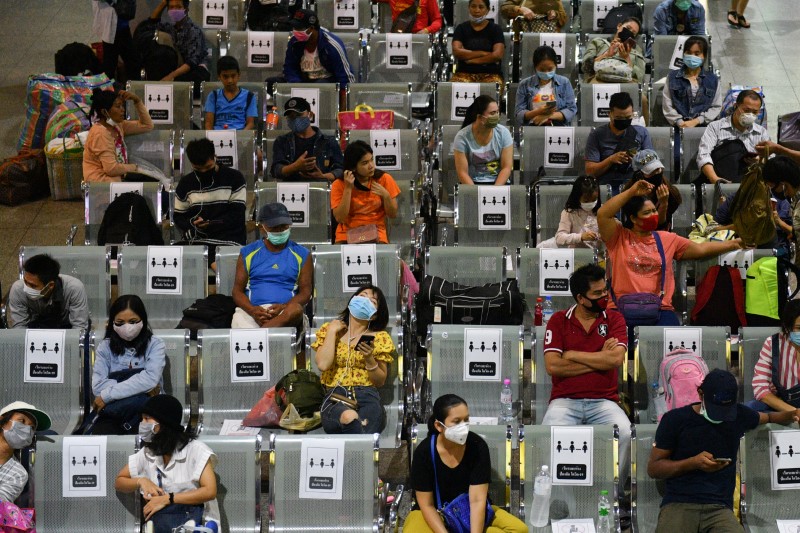 &copy; Reuters. Personas con máscaras faciales de protección, se sientan en bancos de distanciamiento social en una estación de autobuses de Tailandia