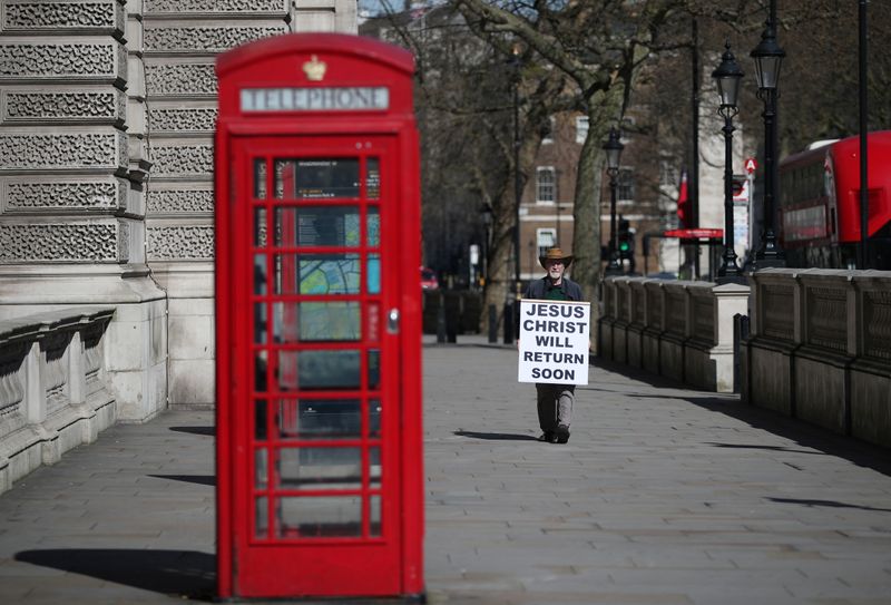 &copy; Reuters. Homem segura cartaz em praça deserta em Londres
