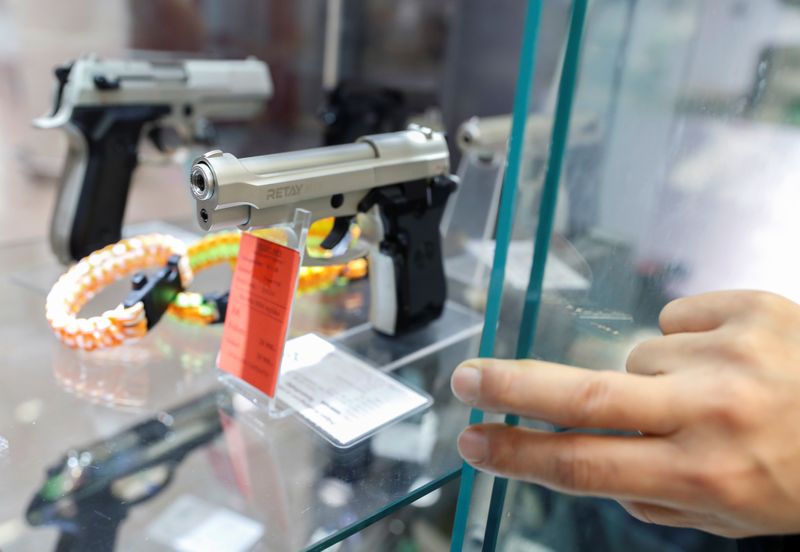 &copy; Reuters. A Hungarian vendor shows an Ekol Firat Magnum gas pistol at a gun shop where people queued up to buy weapons for protection during the coronavirus pandemic, in Budapest