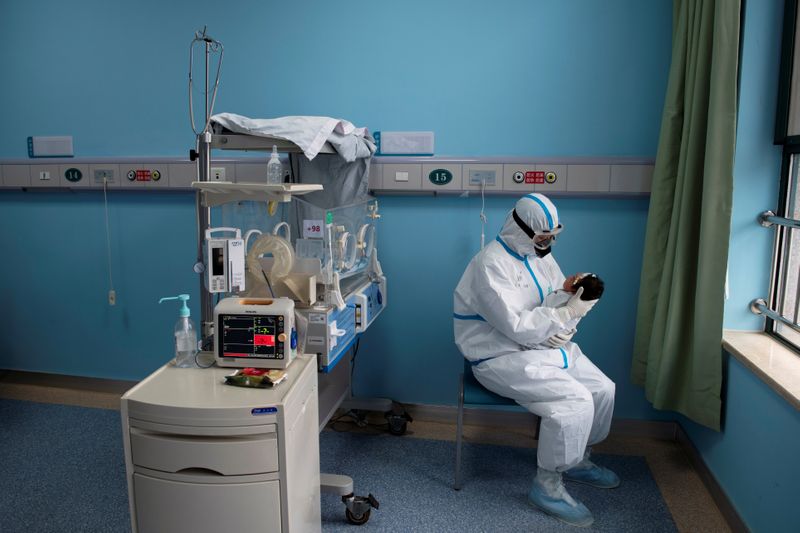 &copy; Reuters. Enfermeira com traje de proteção cuida de bebê com Covid-19 em Wuhan, na China