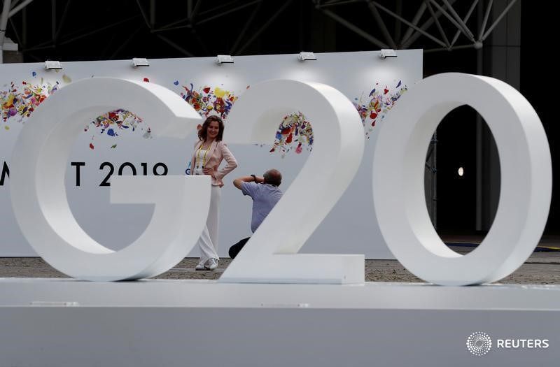 &copy; Reuters. FOTO DE ARCHIVO: una mujer posa para una fotografía junto a un logo de la cumbre del G20 en Osaka, Japón.