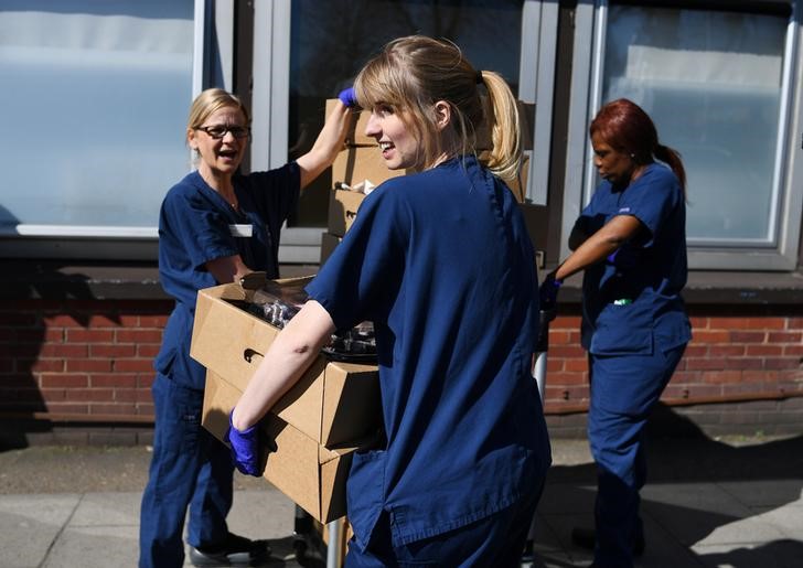 &copy; Reuters. Enfermeras y personal de salud llevan alimentos entregados por voluntarios fuera del hospital Guy and St. Thomas, mientras continúa la propagación del coronavirus (COVID-19), en Londres, Reino Unido.