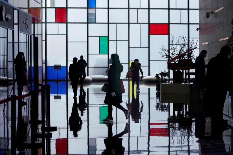 &copy; Reuters. FILE PHOTO: People wearing face masks walk inside an office building at the Lujiazui financial district in Pudong