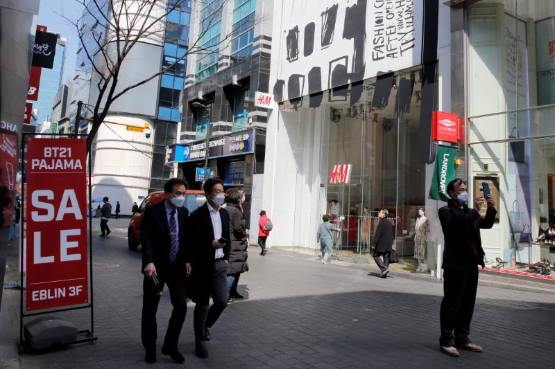 &copy; Reuters. Men wearing masks to prevent contracting coronavirus walk in shopping district in Seoul