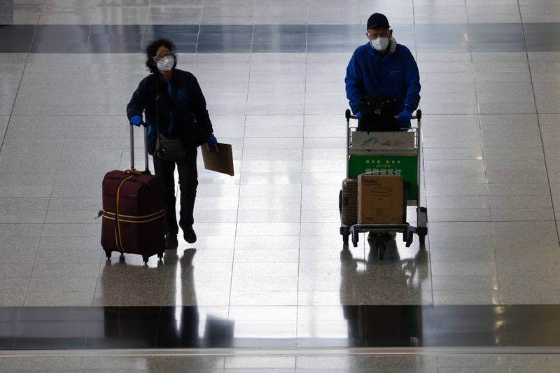 © Reuters. Passengers with protective masks arrive at Hong Kong International Airport, following the novel coronavirus disease (COVID-19) outbreak, in Hong Kong