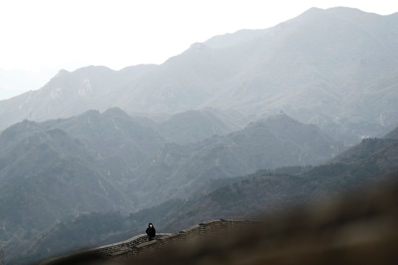 © Reuters. A person wearing a protective mask hikes along a section of the Great Wall in Badaling in Beijing