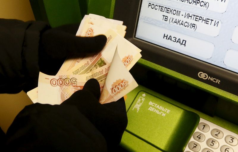 &copy; Reuters. FILE PHOTO: A man counts 5,000 rouble banknotes while he uses a Sberbank ATM in Krasnoyarsk