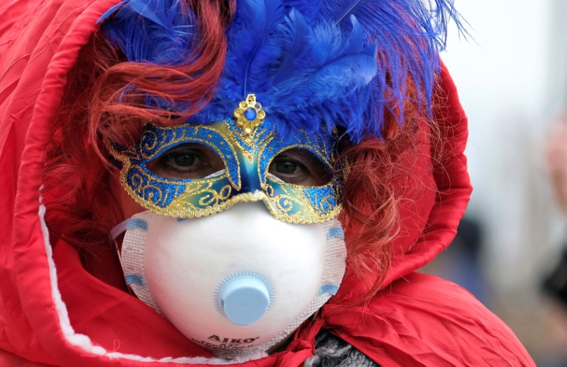 &copy; Reuters. Una persona in maschera indossa una maschera protettiva al Carnevale di Venezia.