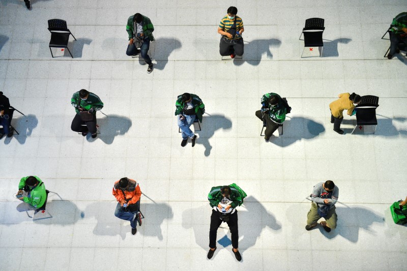 &copy; Reuters. Funcionários de empresas de entrega de alimentos sentam em cadeiras de distância social  em Bangcoc
