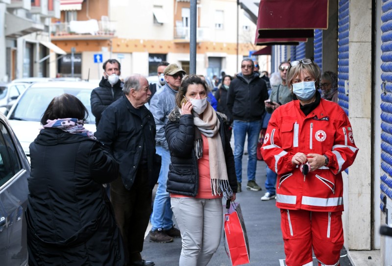 &copy; Reuters. Gente esperando fuera de una tienda de una familia italiana que hace mascarillas caseras que se distribuyen gratuitamente, durante el brote de la enfermedad coronavirus (COVID-19), en la ciudad toscana de Grosseto