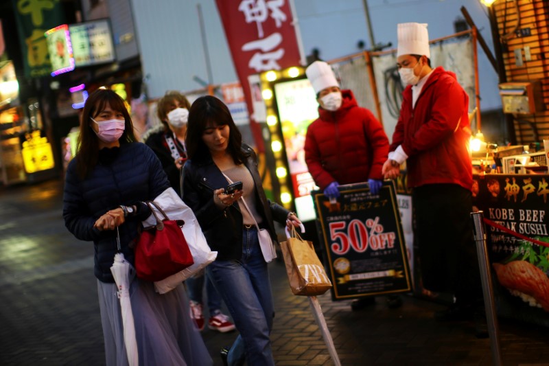 © Reuters. People, wearing protective masks following an outbreak of the coronavirus disease (COVID-19), walk on an almost empty street in the Dotonbori entertainment district of Osaka