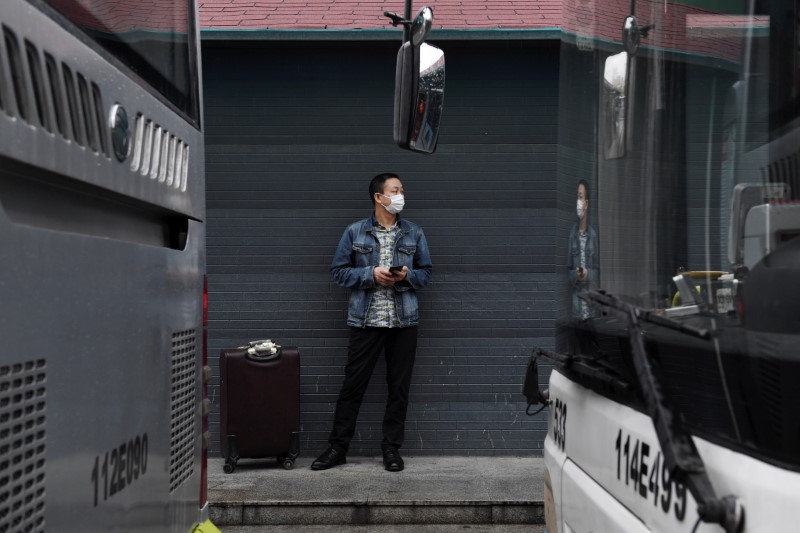 &copy; Reuters. Un hombre que lleva una máscara protectora está de pie junto a una maleta en una terminal de autobuses en Wuhan, donde el transporte público se ha reanudado gradualmente después de una suspensión debido al brote de la enfermedad coronavirus (COVID-19