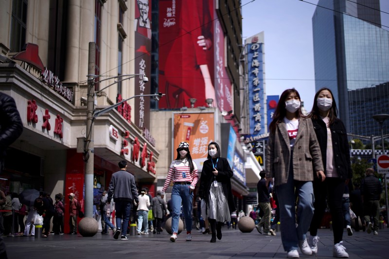 &copy; Reuters. FOTO DE ARCHIVO: Gente usa máscaras en una zona comercial principal después de que el nivel de alerta de emergencia de la ciudad por la enfermedad del coronavirus (COVID-19) se redujera, en Shanghái, China