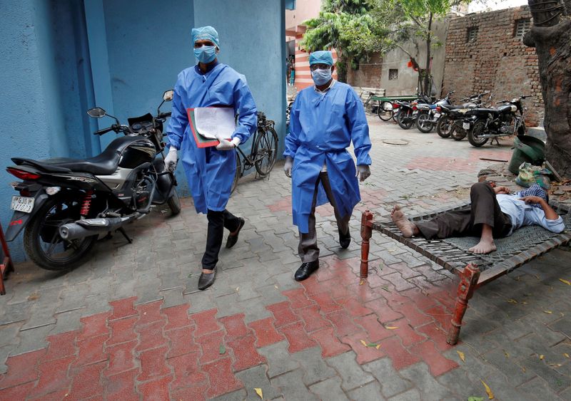 © Reuters. Police officers in protective suits arrive in a residential area to check on people under home quarantine in Ahmedabad