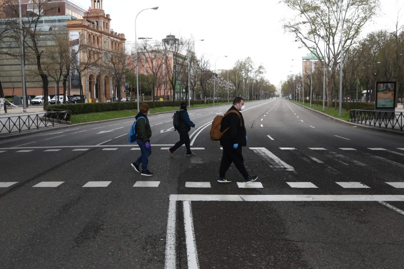 &copy; Reuters. Personas con máscaras protectoras mantienen el distanciamiento social al cruzar una calle casi desierta del Paseo de la Castellana durante el brote de la enfermedad coronavirus (COVID-19), en Madrid España