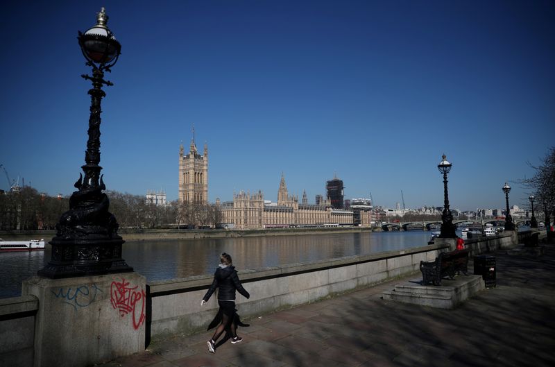 &copy; Reuters. Una mujer camina frente a las Cámaras del Parlamento británico, en la ribera del río Támesis, mientras continúa la propagación del coronavirus en Londres