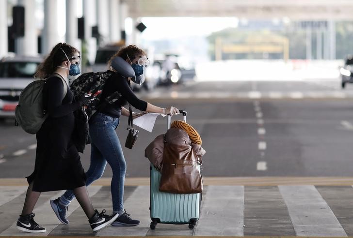 &copy; Reuters. Mulheres com roupa de proteção no aeroporto de Garulhos