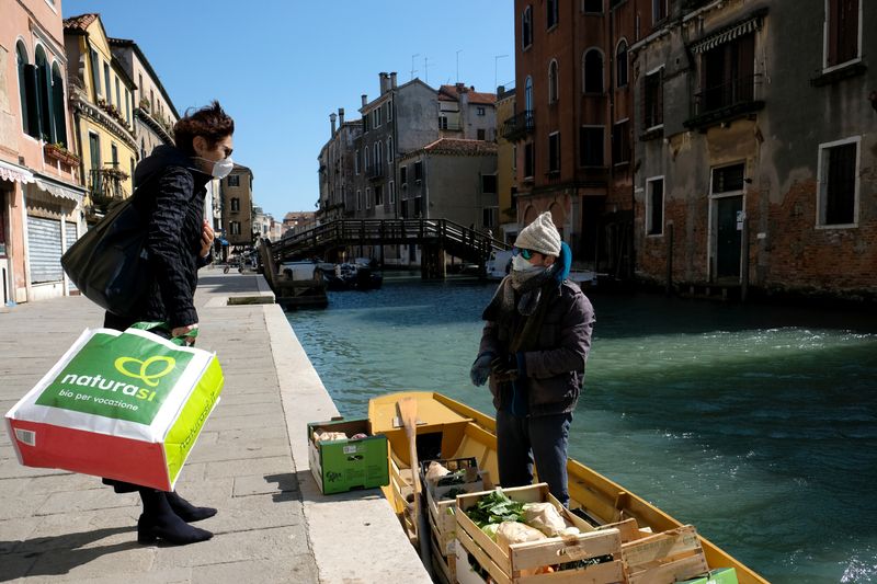 &copy; Reuters. Homem entrega frutas e vegetais de balsa para clientes durante quarententa por coronavírus em Veneza