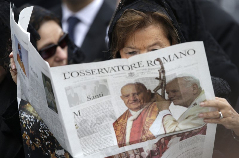 © Reuters. Mulher lê o periódico do Vaticano, 