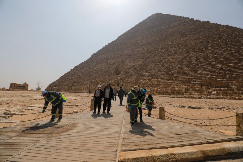 &copy; Reuters. Membros de equipes de saúde usam desinfentante em área das pirâmides do Egito, nos arredores do Cairo