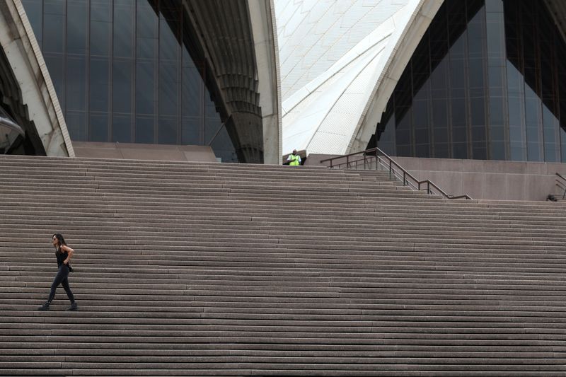 &copy; Reuters. A woman walks on the mostly deserted steps of the Sydney Opera House