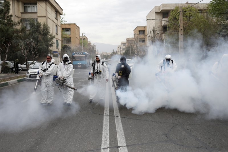 &copy; Reuters. FILE PHOTO: Members of firefighters wear protective face masks, amid fear of coronavirus disease, as they disinfect the streets, ahead of the Iranian New Year Nowruz, March 20, in Tehran